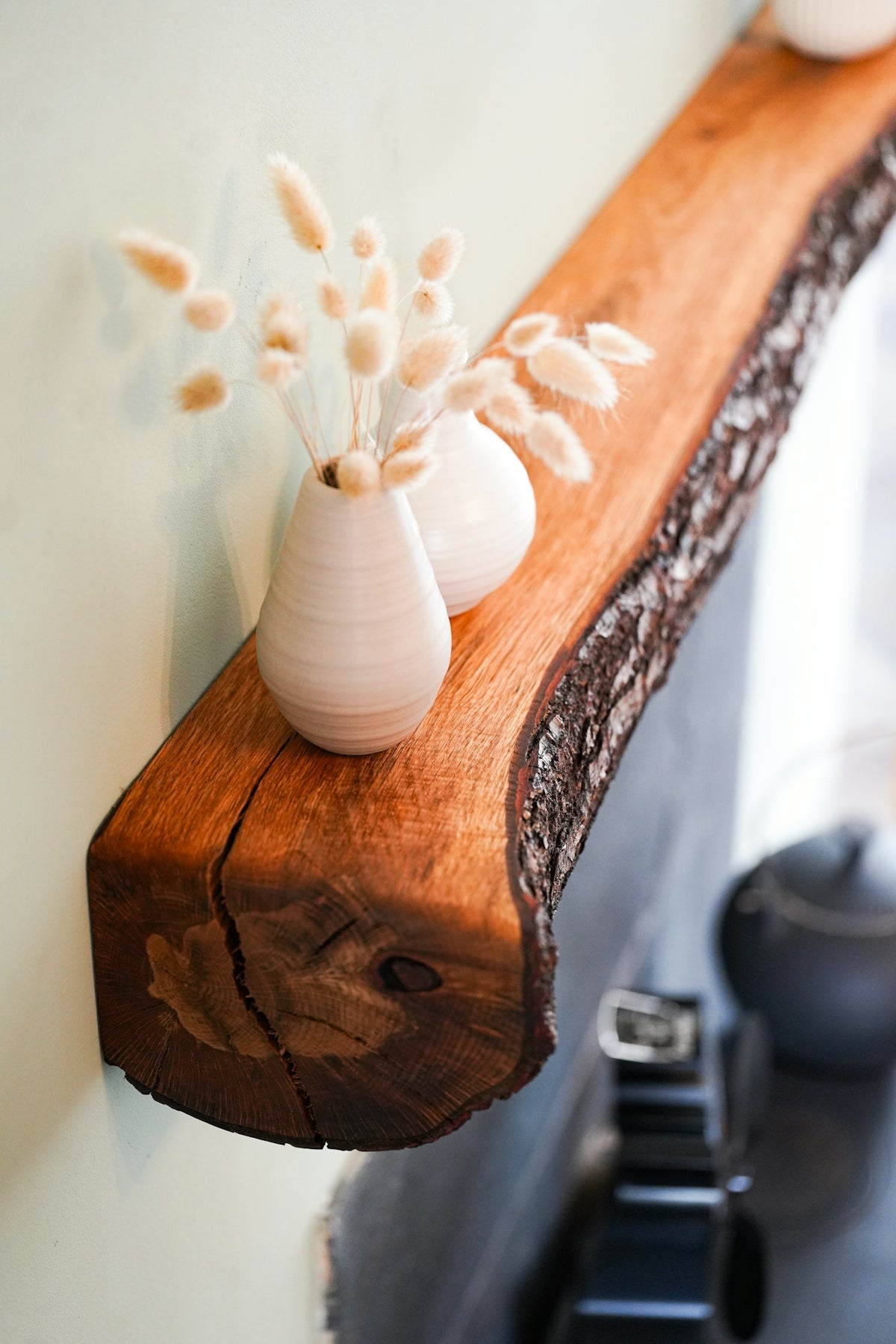 Wooden shelf with decorative vases and dried flowers.