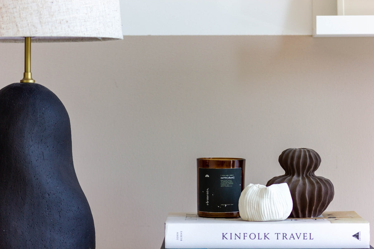 A dark lamp, candle, and decorative objects on books.