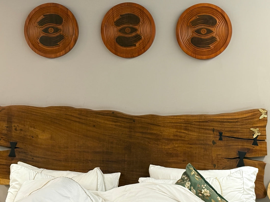 Three wooden wall hangings above a bed